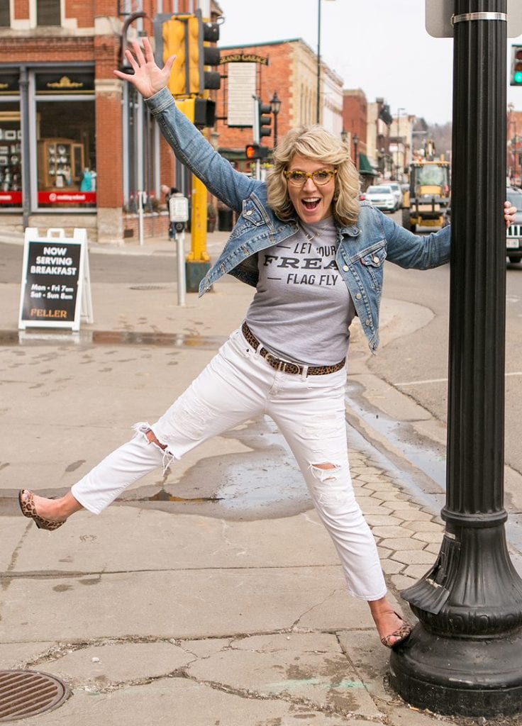 Jen Bertsch holding on to a lamp post and kicking her leg and arm in the air with excitement!